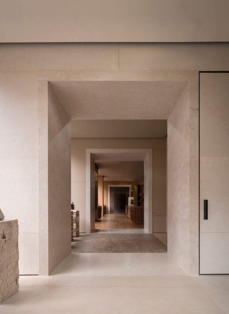 A wide view through the stone thresholds of the enfilade, moving from a bright stone room towards a warmer wood-toned interior.