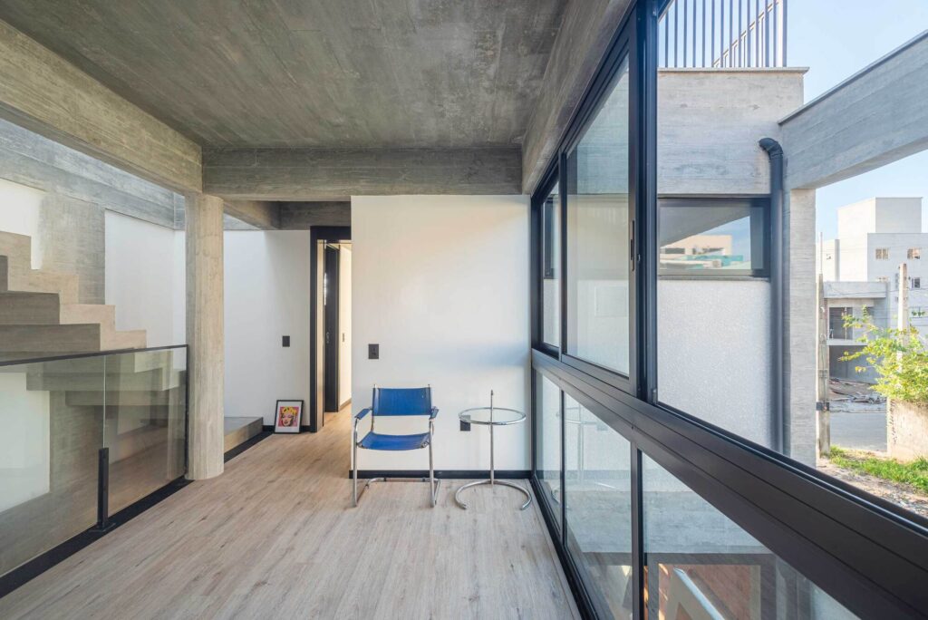 Upper floor corridor with large glass windows overlooking the courtyard and wood-textured flooring.