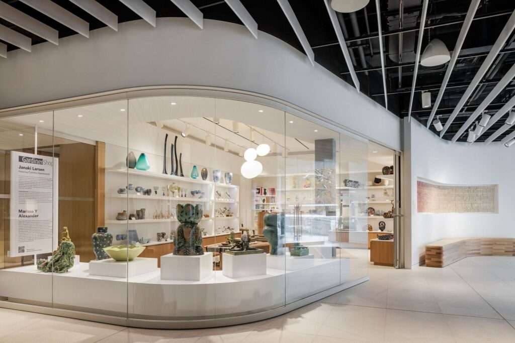 The Gardiner Shop featuring curved glass windows and white shelving displaying various ceramic art pieces.