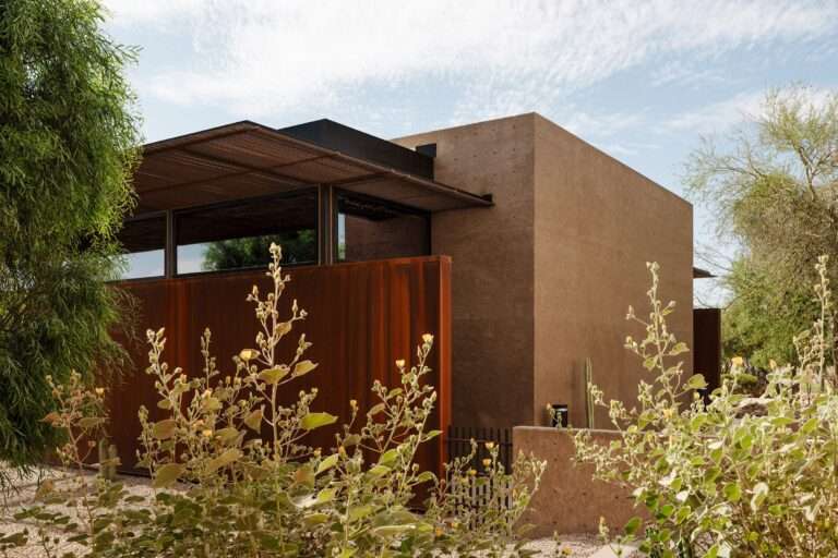 Cocopah Museum extension showing pigmented concrete volume and weathering steel wall behind desert vegetation