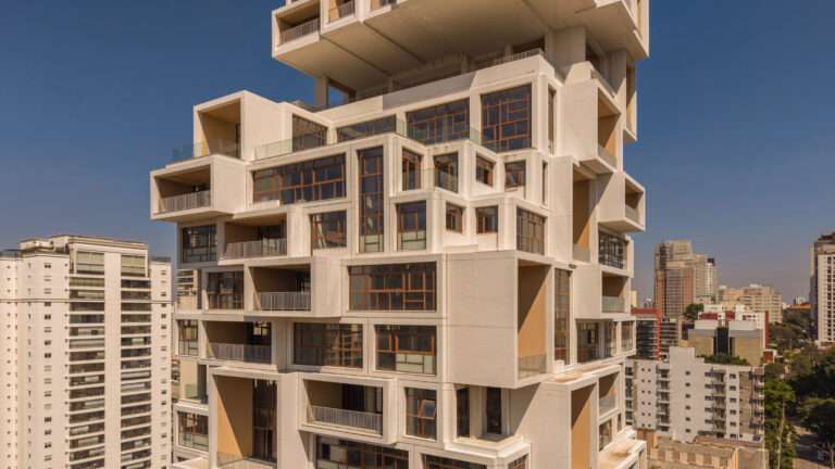 Close-up view of a white tiled building with protruding rectangular volumes and integrated balconies.