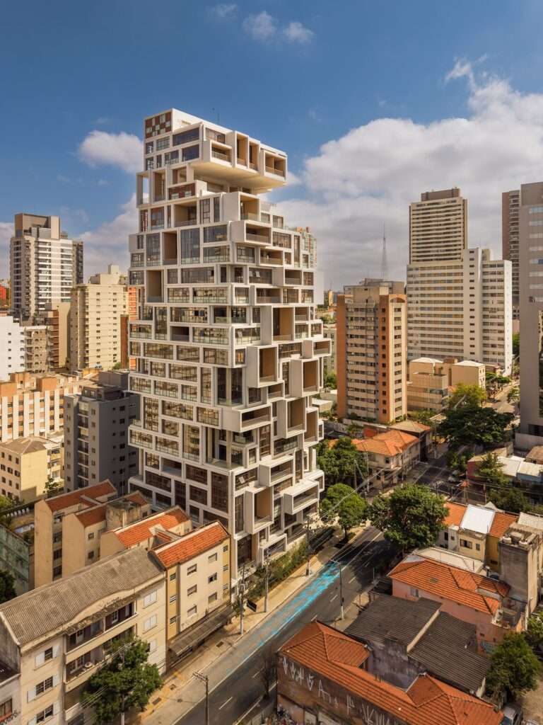 Street-level perspective view of a white multi-level tower with staggered volumes and balconies.