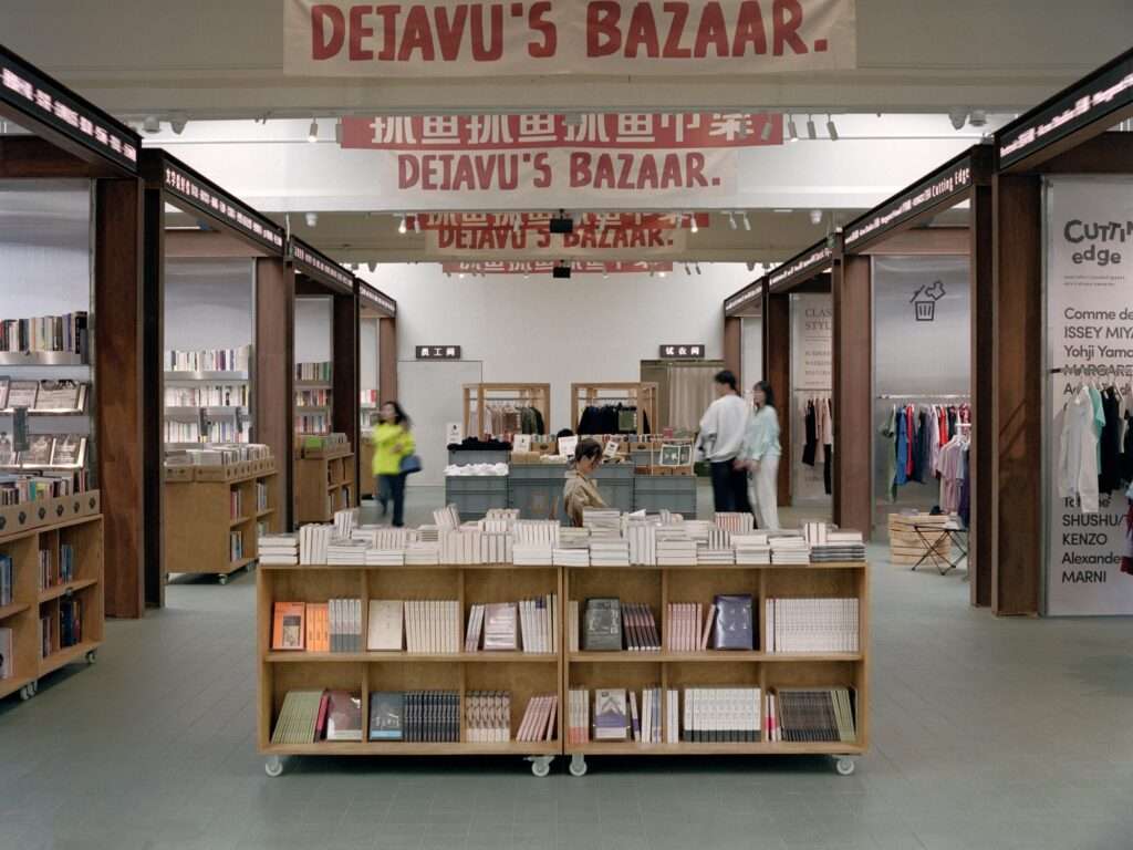 Interior view of the Deja Vu recycle store featuring eight weathered steel frames that divide the space into two distinct display zones with a central atrium plaza.