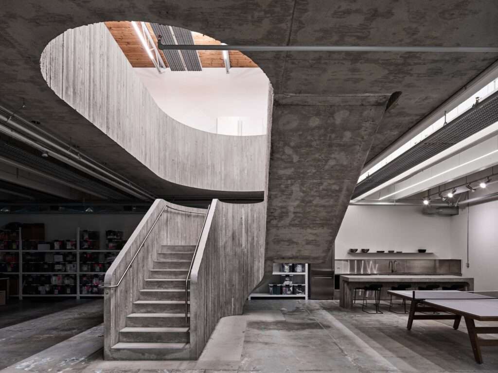 Brutalist central concrete staircase in the Purple Brand Operations Studio, Vancouver, showing the connection between industrial floors and exposed raw materials.