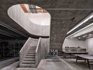 Brutalist central concrete staircase in the Purple Brand Operations Studio, Vancouver, showing the connection between industrial floors and exposed raw materials.
