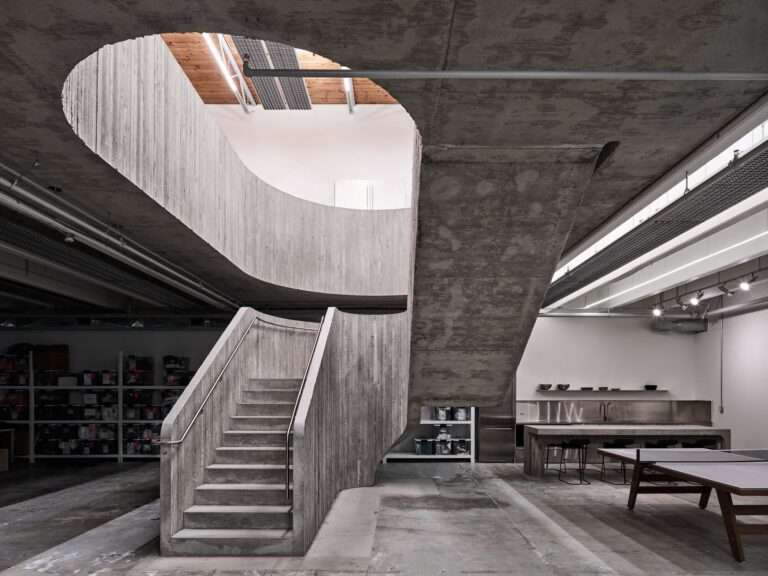 Brutalist central concrete staircase in the Purple Brand Operations Studio, Vancouver, showing the connection between industrial floors and exposed raw materials.