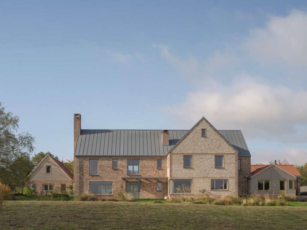Front elevation of a contemporary rural house in North Hertfordshire featuring brick and flint facades with a zinc gabled roof.