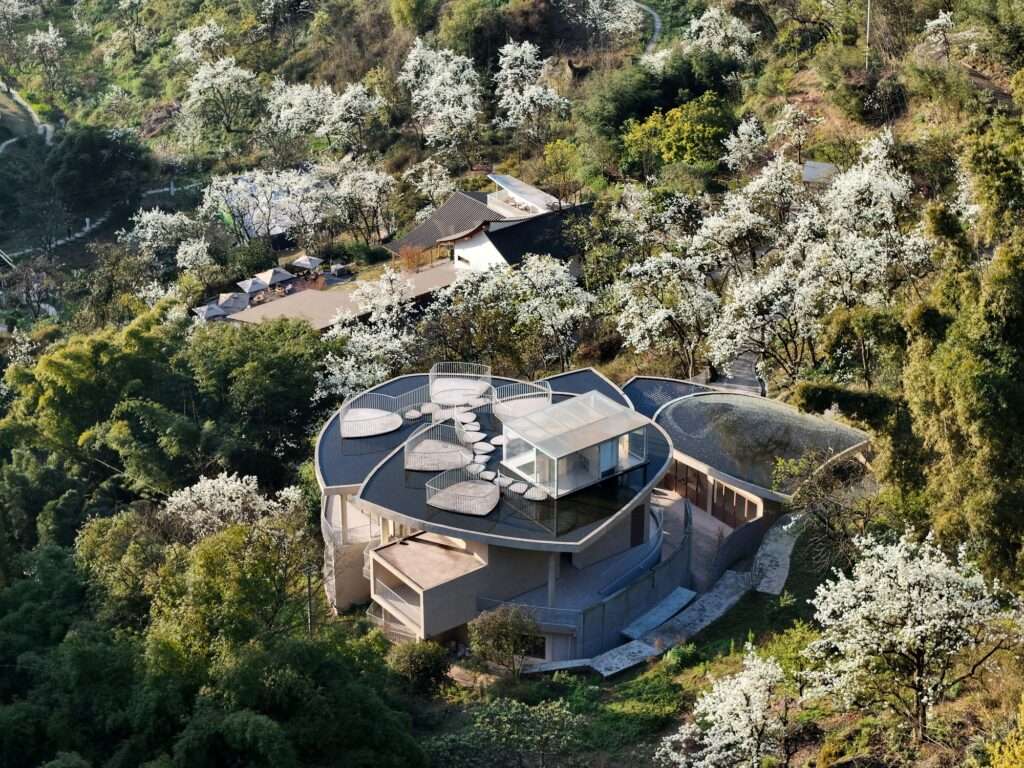 A large circular architectural opening in a concrete wall connecting two activity halls within the Feixiuwei Pavilion.