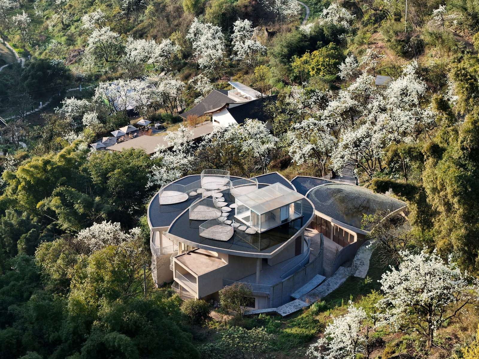 A large circular architectural opening in a concrete wall connecting two activity halls within the Feixiuwei Pavilion.
