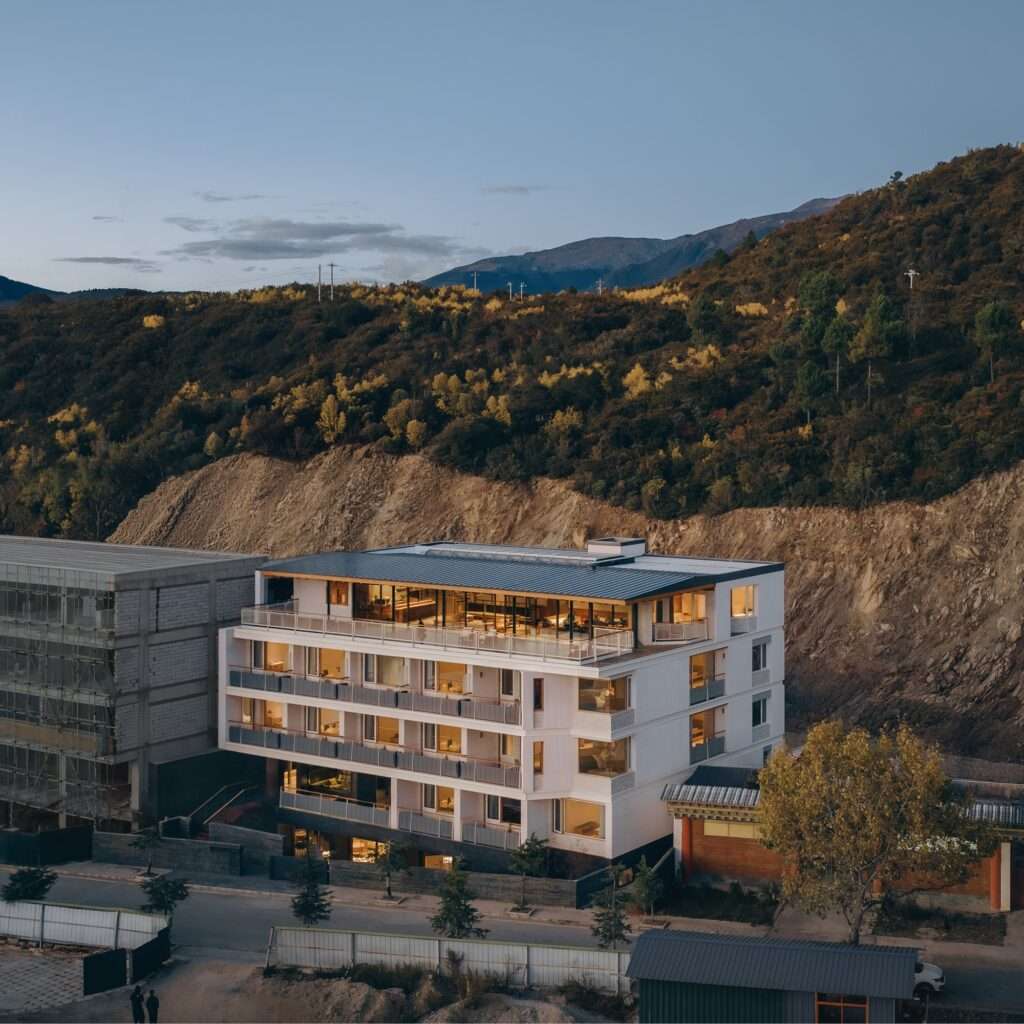 Exterior of Kawagebo Snow Mountain Hotel featuring a white sandstone facade against a mountain backdrop in Deqin Yunnan.