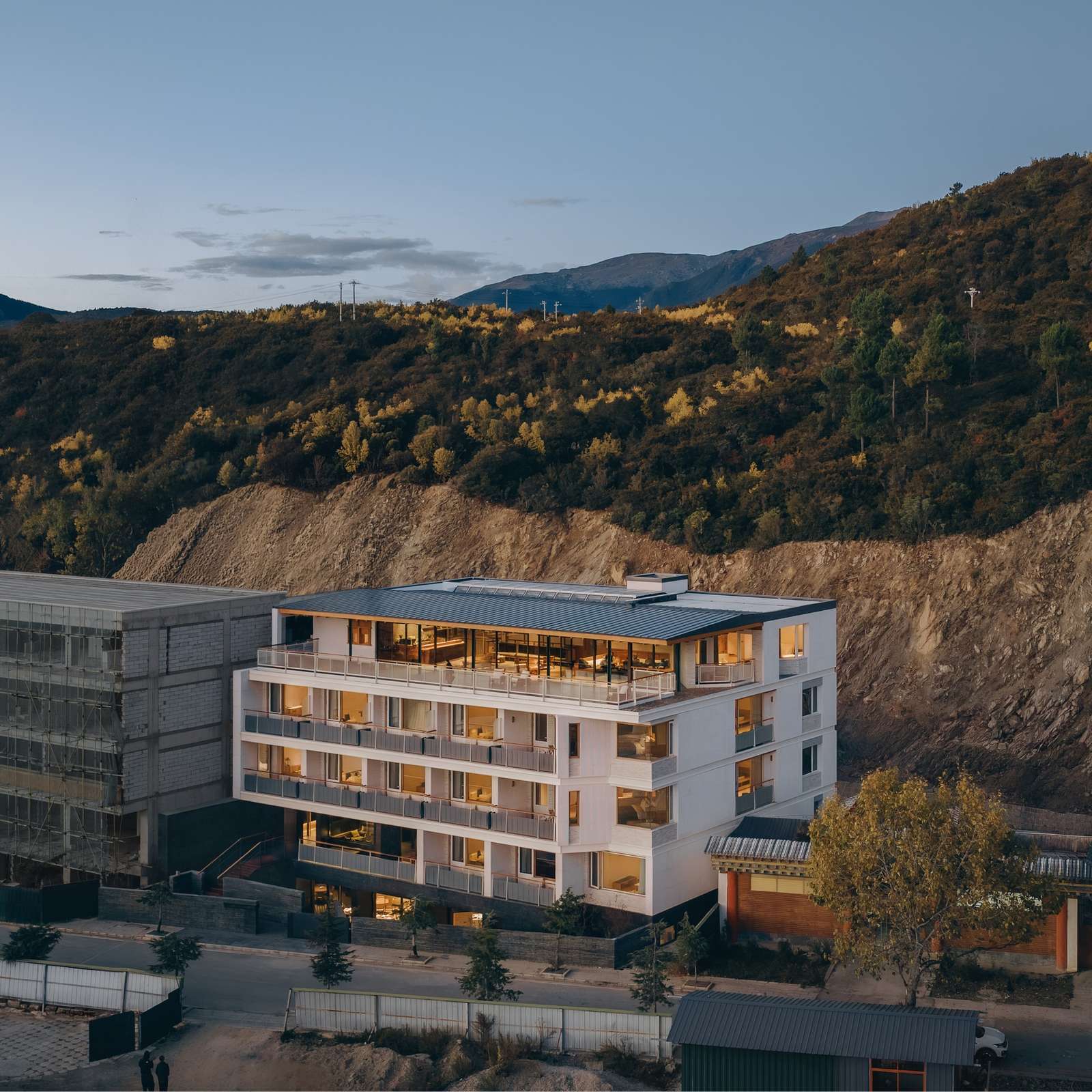 Exterior of Kawagebo Snow Mountain Hotel featuring a white sandstone facade against a mountain backdrop in Deqin Yunnan.