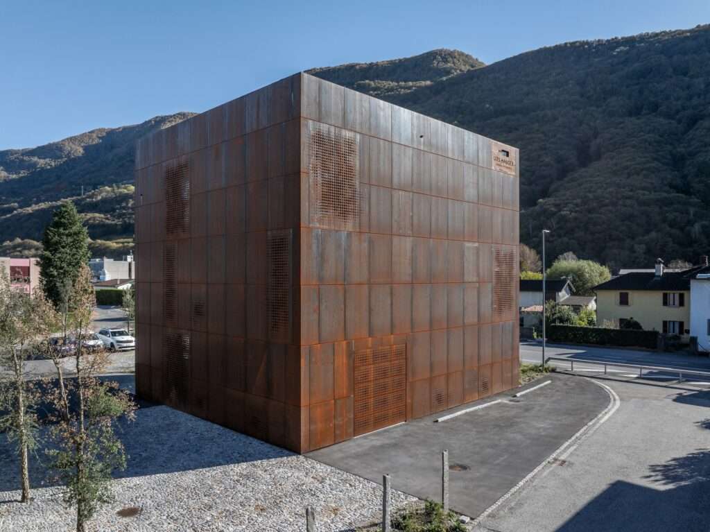 Detailed view of the Cantina Hauser facade showing the irregular laser-cut perforations in the Corten steel panels for natural ventilation and light control.