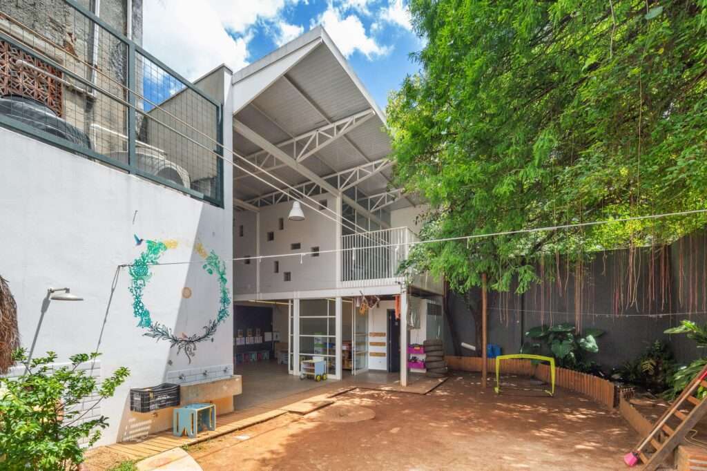 Modern lightweight school extension featuring a transparent structure and high ceilings adjacent to a green play area.