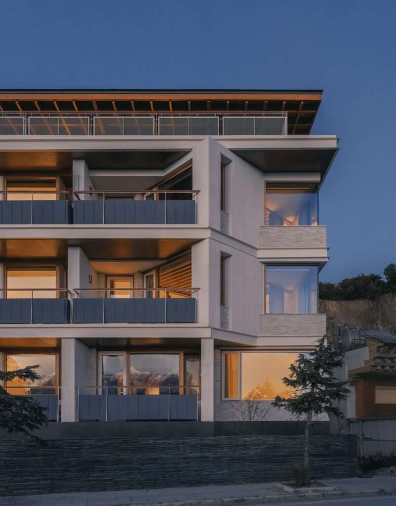 Close-up detail of the white sandstone facade and grey fabric railings of Kawagebo Snow Mountain Hotel at dusk.