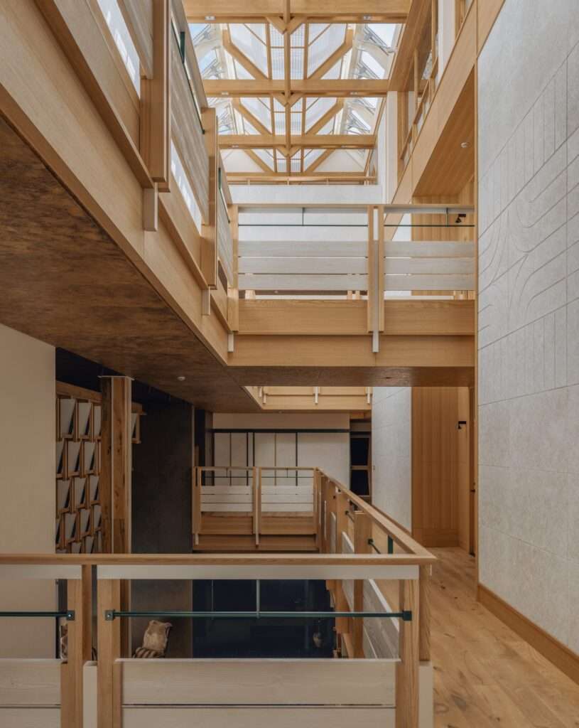 Interior view of the vertical central atrium in Kawagebo Hotel with timber frames and a glass skylight.