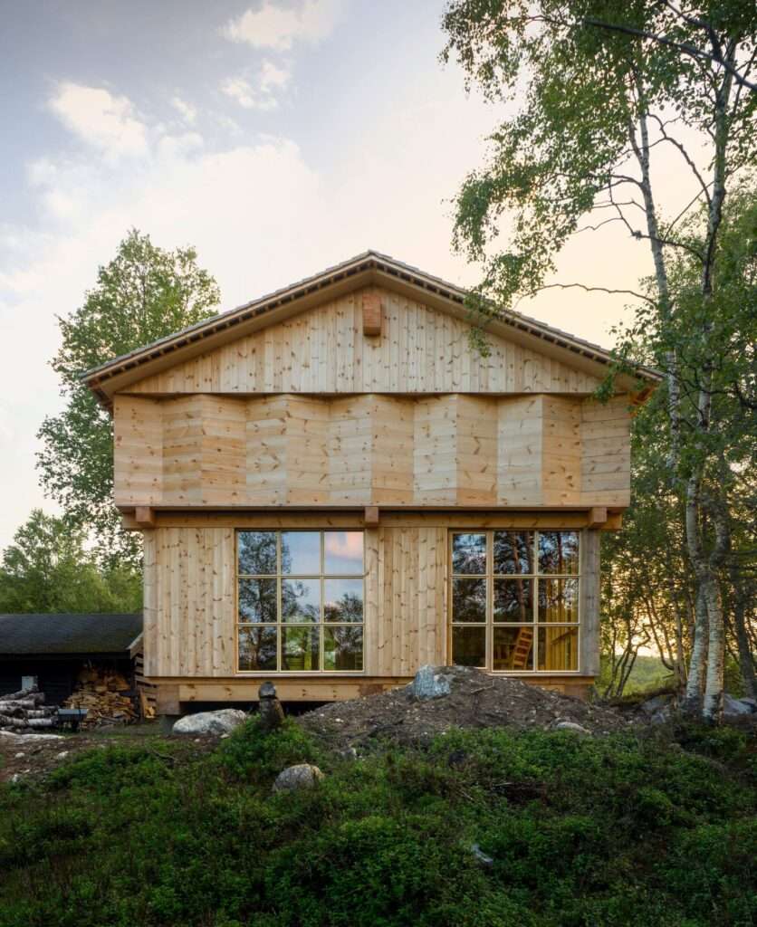 Close-up of the Timber Temple cabin facade featuring Spruce wood cladding and large grid-pattern windows.
