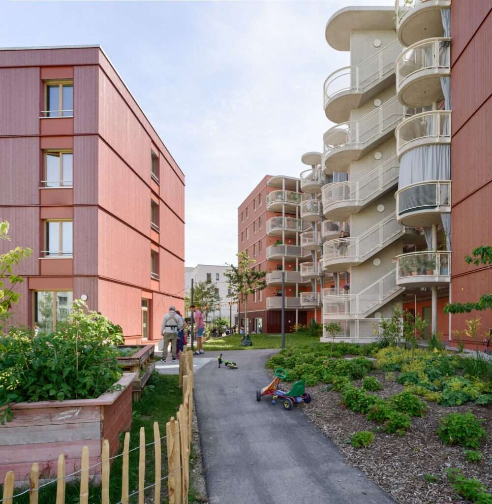 Internal courtyard pathway with a concrete prefabricated access balcony walkway and circular balconies in a Munich cooperative housing project.