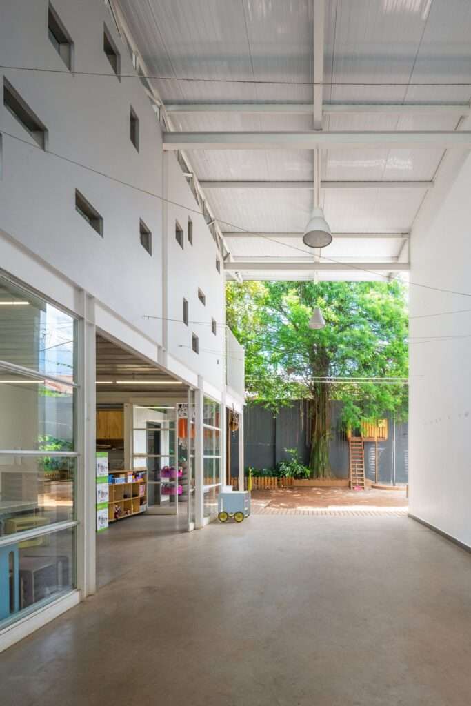 Interior corridor of the school extension with minimalist white walls, small square windows, and natural light.