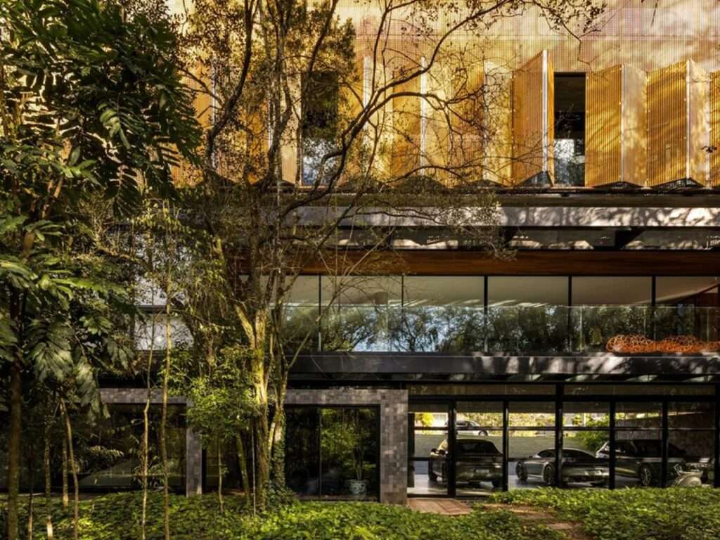Modern facade of House 17-JB showing perforated wooden screens, glass walls, and a luxury car gallery at the ground level.