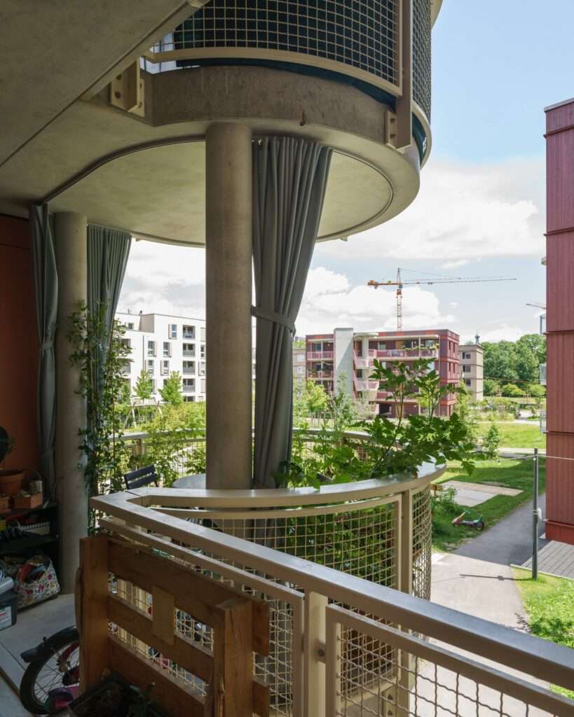 Close-up view from a circular concrete balcony looking out toward a construction site and neighboring blocks in Freiham development.