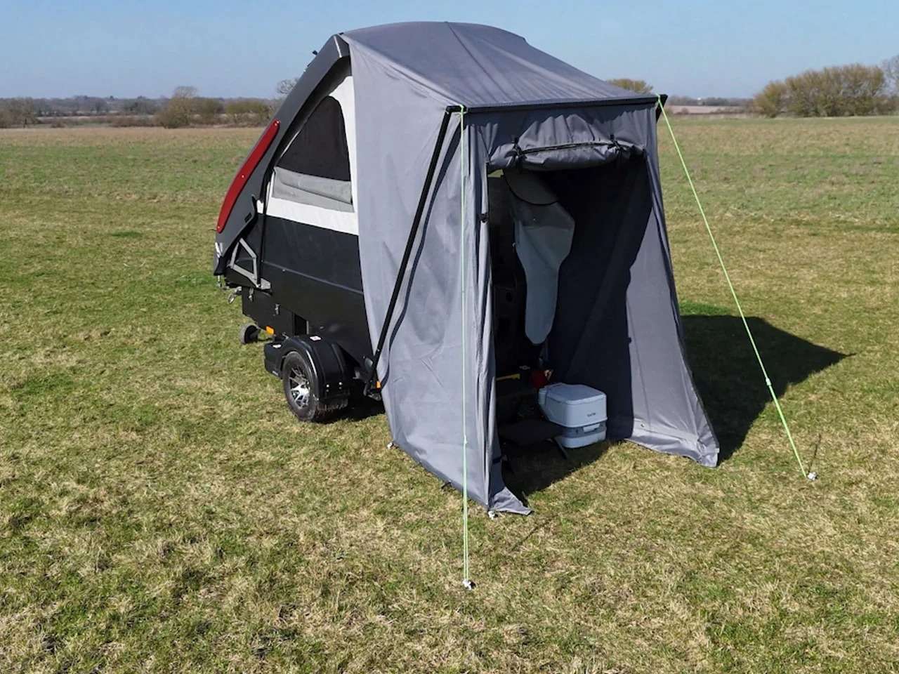 Rear view of Dashaway ECT trailer with grey awning extension fully deployed in a grassy field.