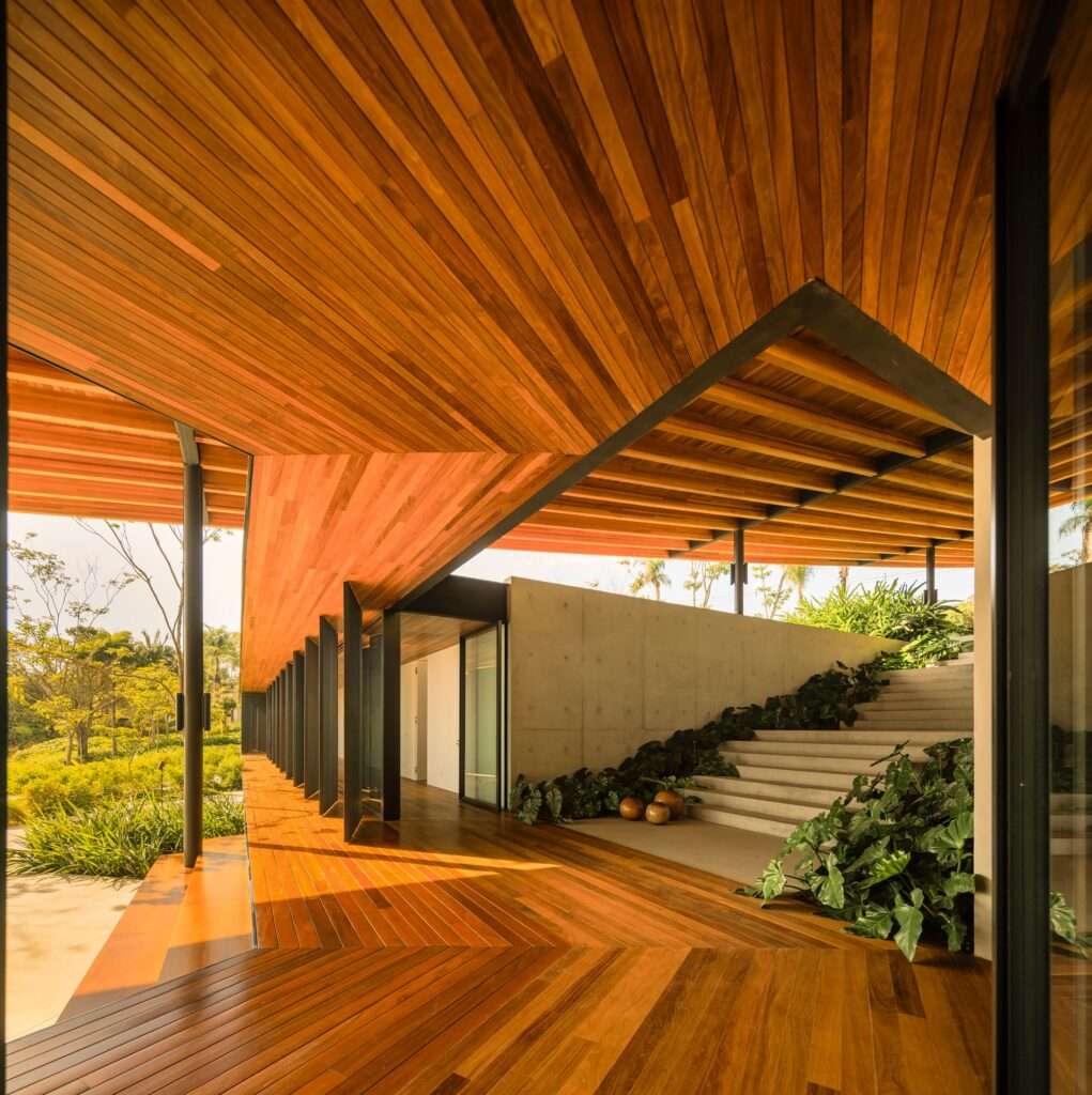 Interior of a modern open-plan living and dining area with wood ceiling and rotating slatted wood facade panels.