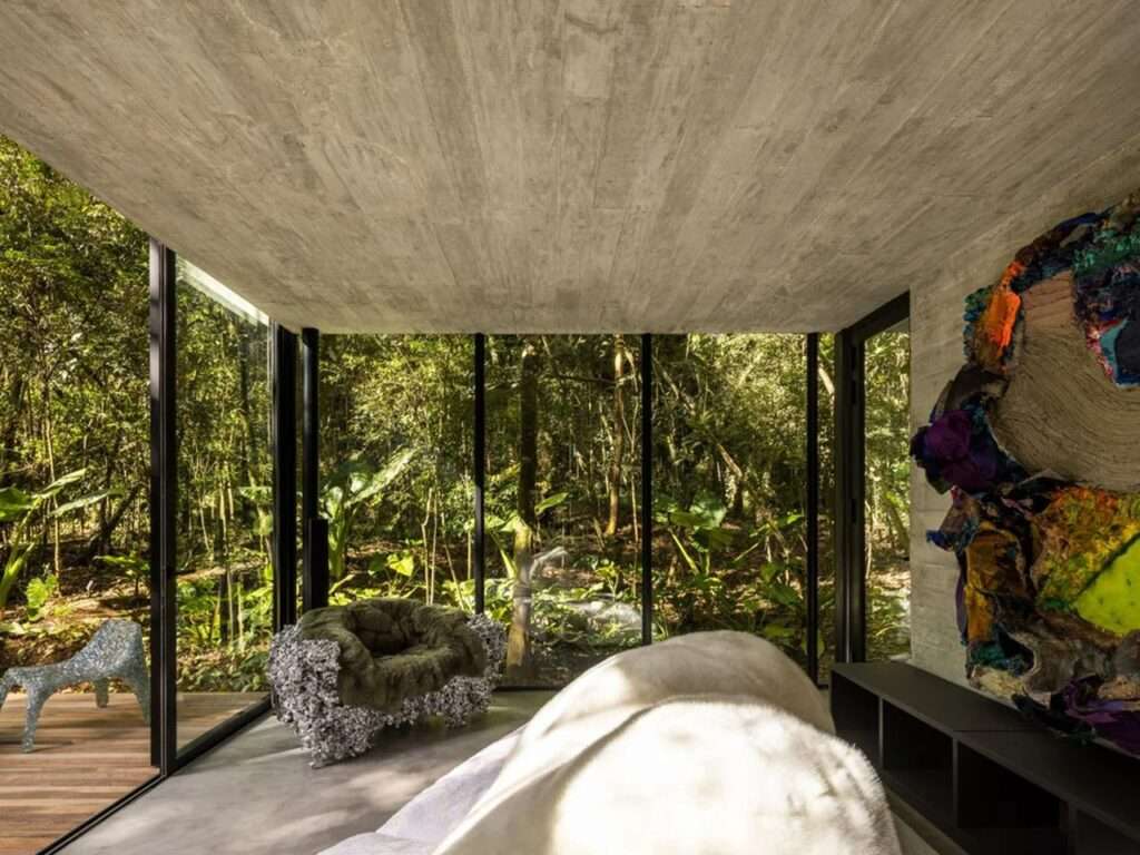 Interior of the lower glass pavilion in House 17-JB with a large abstract wall art and views of the surrounding native forest.