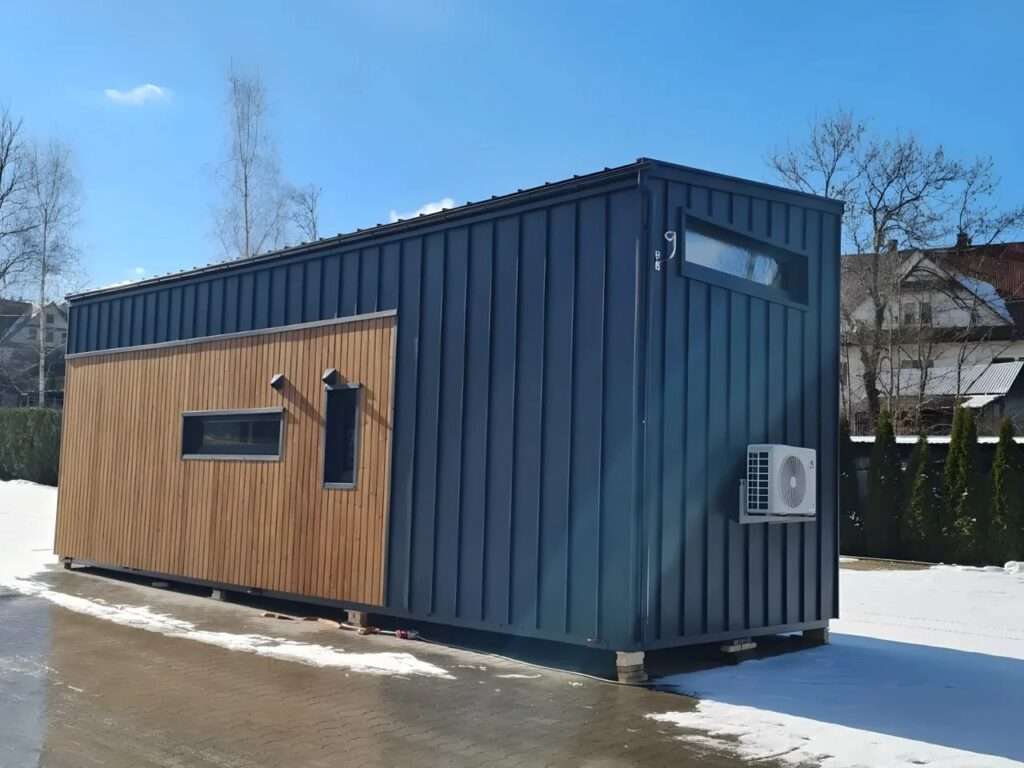 Side profile of the Samuel permanent tiny house featuring grey metal siding and a mounted air conditioning unit.