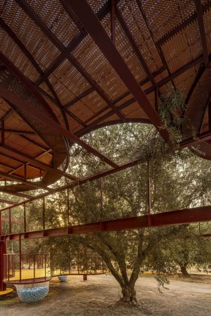 Underneath view looking up at a perforated plastic floor platform and a steel frame cradling an olive tree branch.