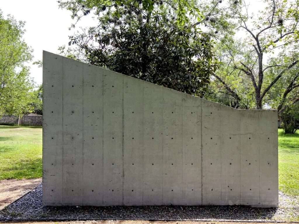 Side elevation of the minimalist Oratory Chapel by S-AR, showcasing the clean lines of the concrete form against the sky.