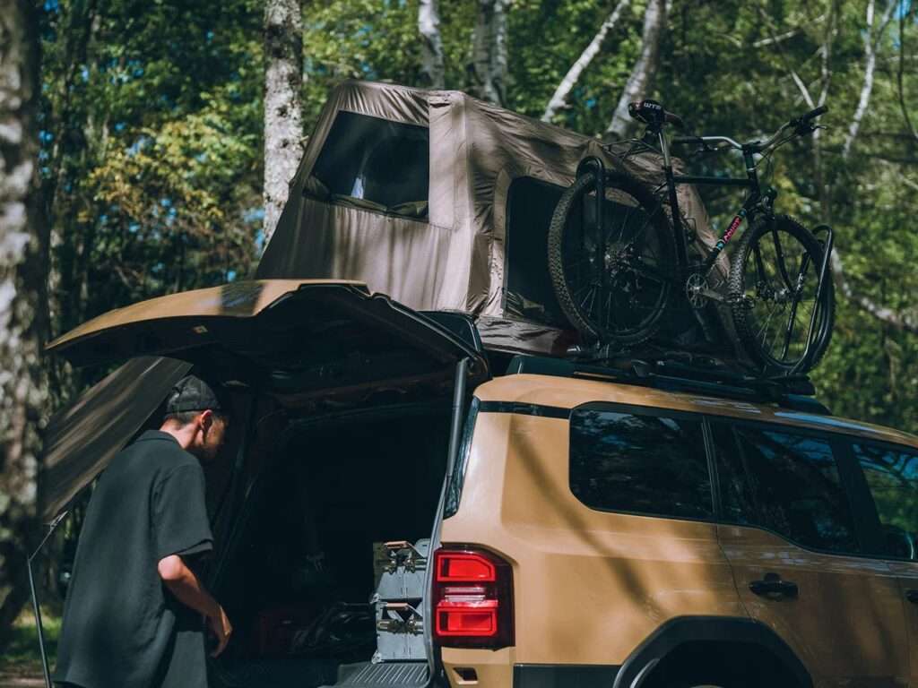 The Fire Rise RTT mounted on a vehicle roof alongside a bicycle rack, showcasing efficient space management.