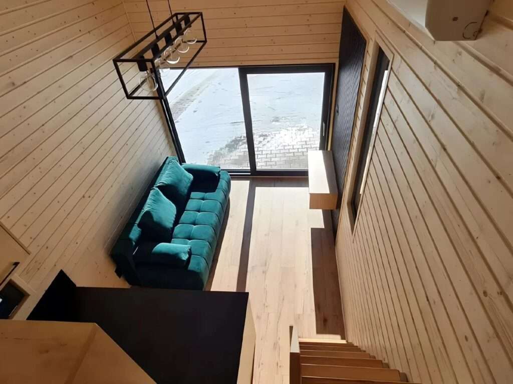 High-angle interior view of the Samuel living area featuring a teal sofa and light wood paneling.