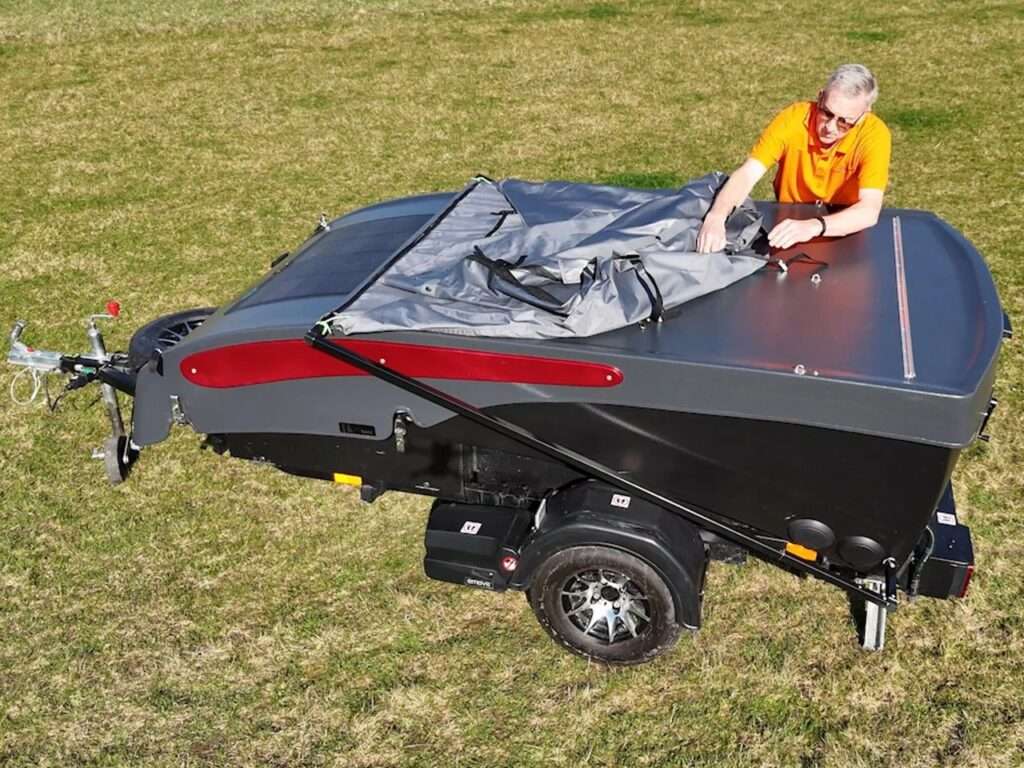 A man adjusting the roof of a Dashaway ECT trailer in its lowered 3.8-foot driving configuration.