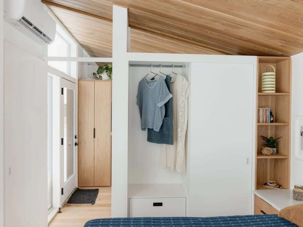 Interior of the primary bedroom in the Halcyon Grand showing white built-in wardrobes, a hanging clothing rod, and custom light wood shelving.