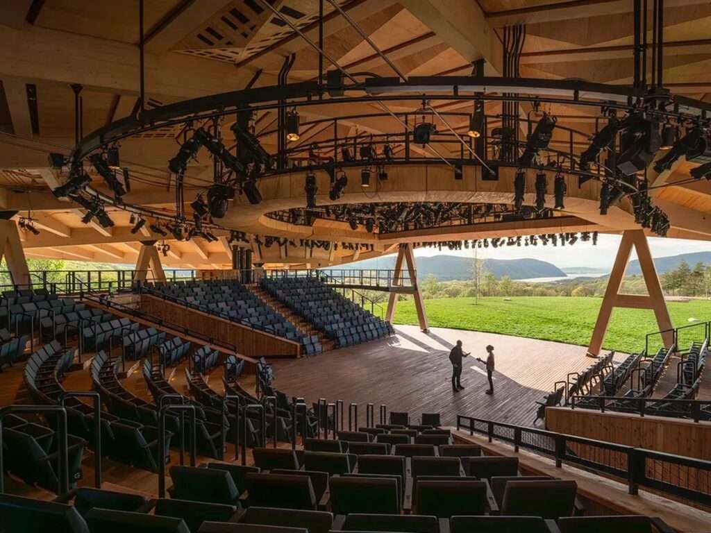 Inside the Samuel H. Scripps Theater showing the wooden stage, tiered seating, and overhead stage production lighting rigs looking out to the mountains.