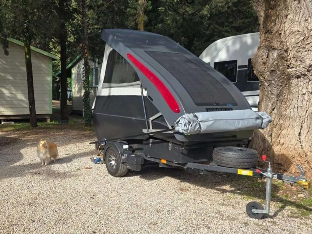 Dashaway ECT trailer parked in a campsite showing the roof-mounted solar panel and side fabric walls.