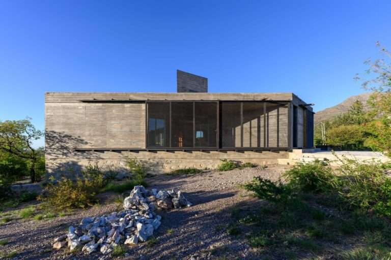 Side exterior view of Casa Cosmos highlighting the texture of exposed concrete and deep architectural galleries.