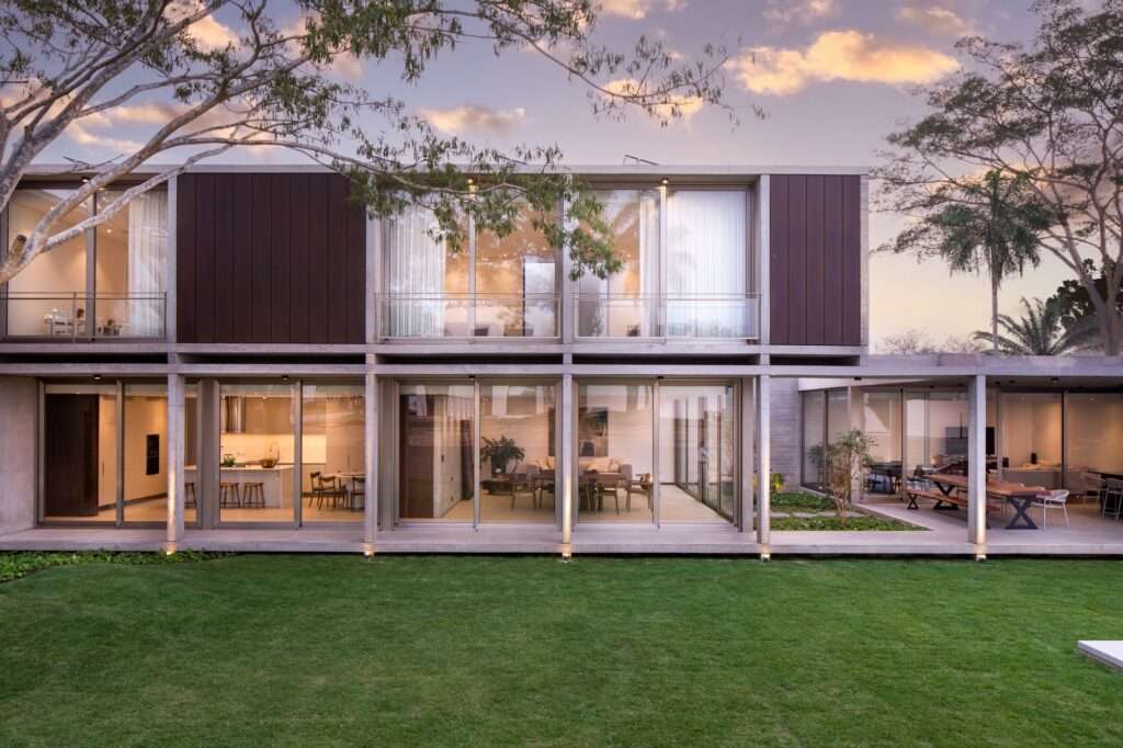 Twilight exterior view of Casa Jevio showing the rear garden elevation and the long horizontal massing.