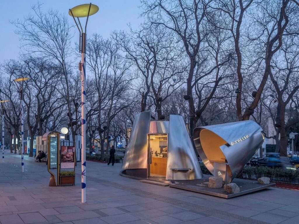 Street-level view of the reflective Kurasu coffee kiosk situated along a wide pedestrian plaza in Taikoo Li Sanlitun, Beijing.