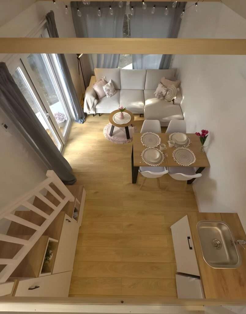 Top-down view of the Smile house interior showing the living room, dining set, and wooden flooring layout.