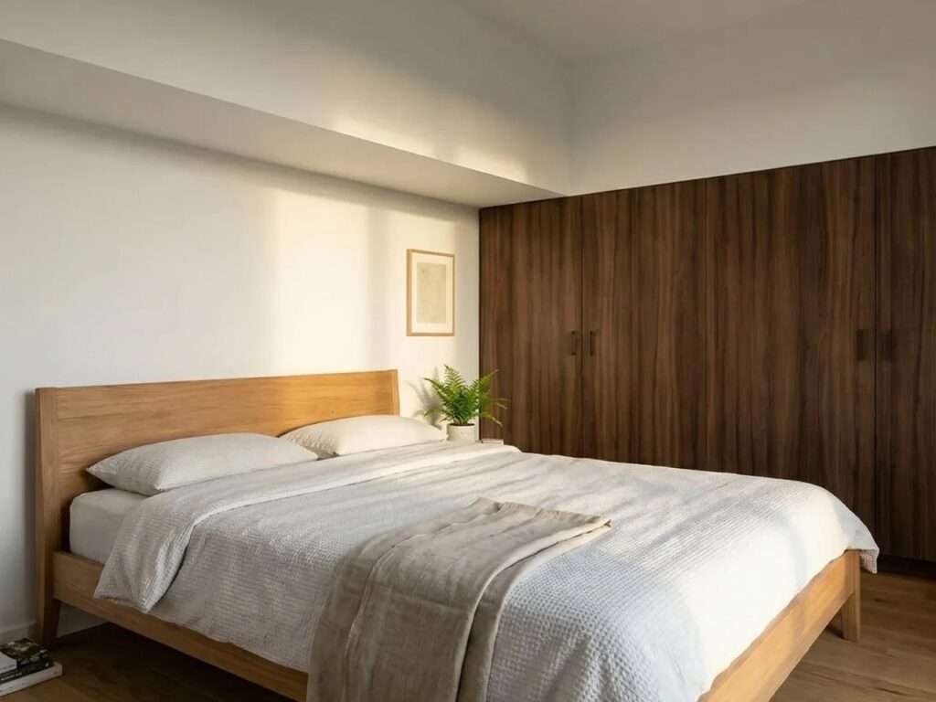 Ground floor master bedroom in the SOMA tiny house with minimalist wooden bed frame and large integrated walnut wardrobes.