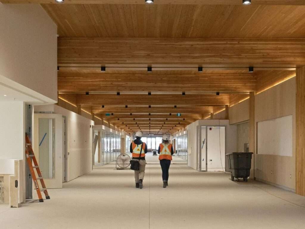 Long interior view of the main corridor in Marpole Community Centre featuring a repetitive Glulam beam ceiling and integrated track lighting.