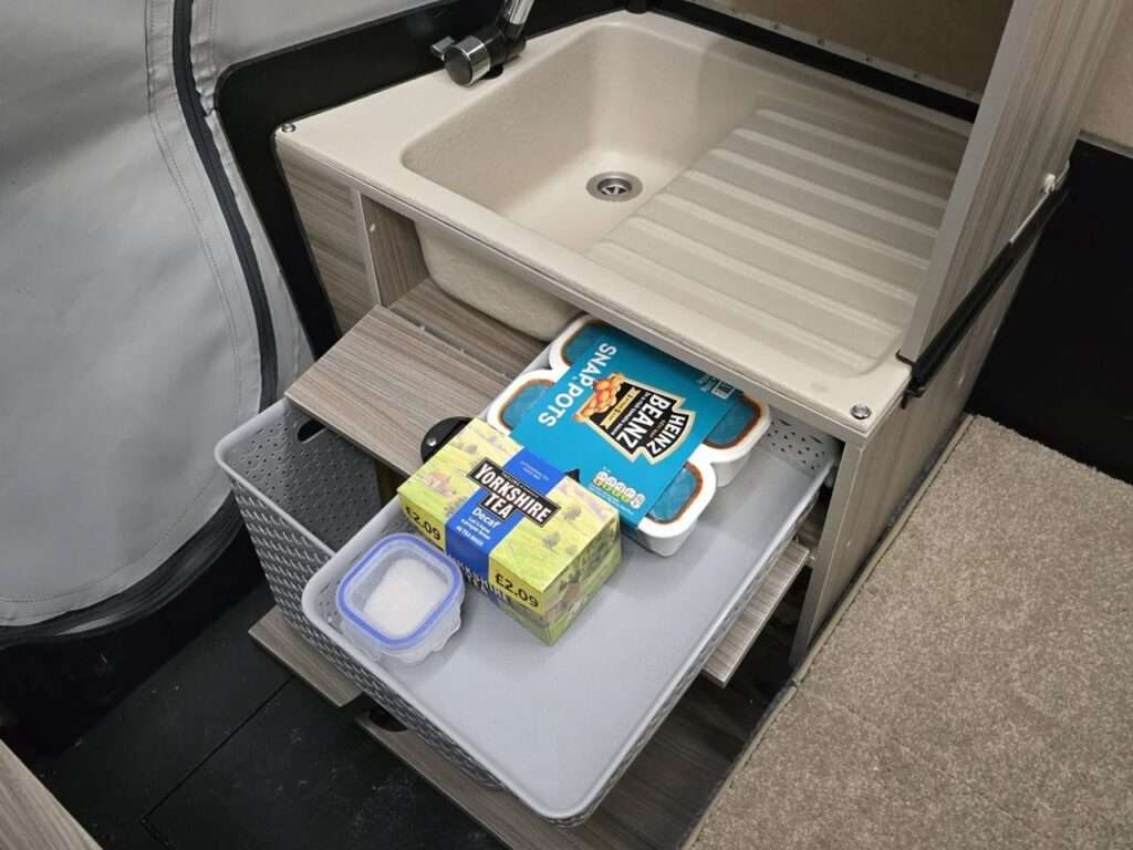 Close-up of the compact internal sink and pull-out storage drawer with kitchen supplies in a Dashaway ECT.