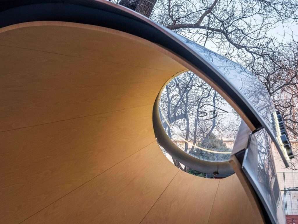 Close-up interior view of the smaller cantilevered volume showing wood-grained aluminum lining and a circular glass skylight.