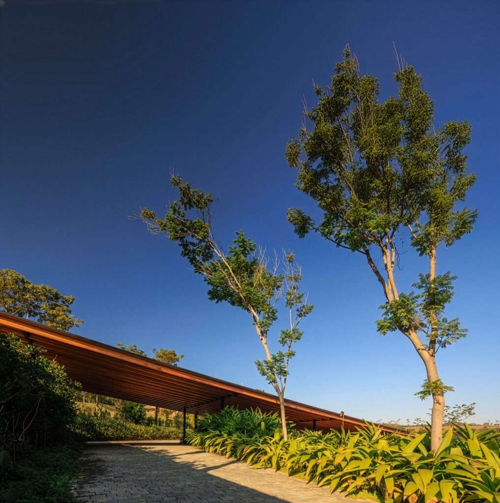 A distant view of a modern pavilion-style house surrounded by trees on the edge of a large lake or reservoir.