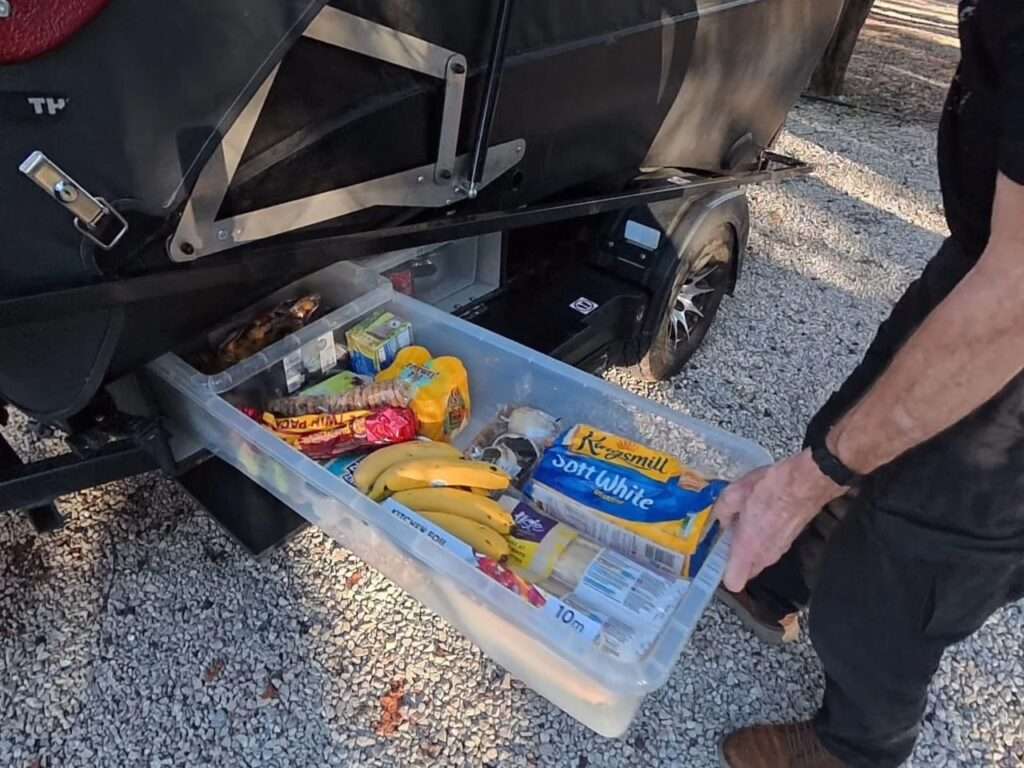 A man pulling out a large transparent storage drawer from the lower chassis of the Dashaway ECT trailer.