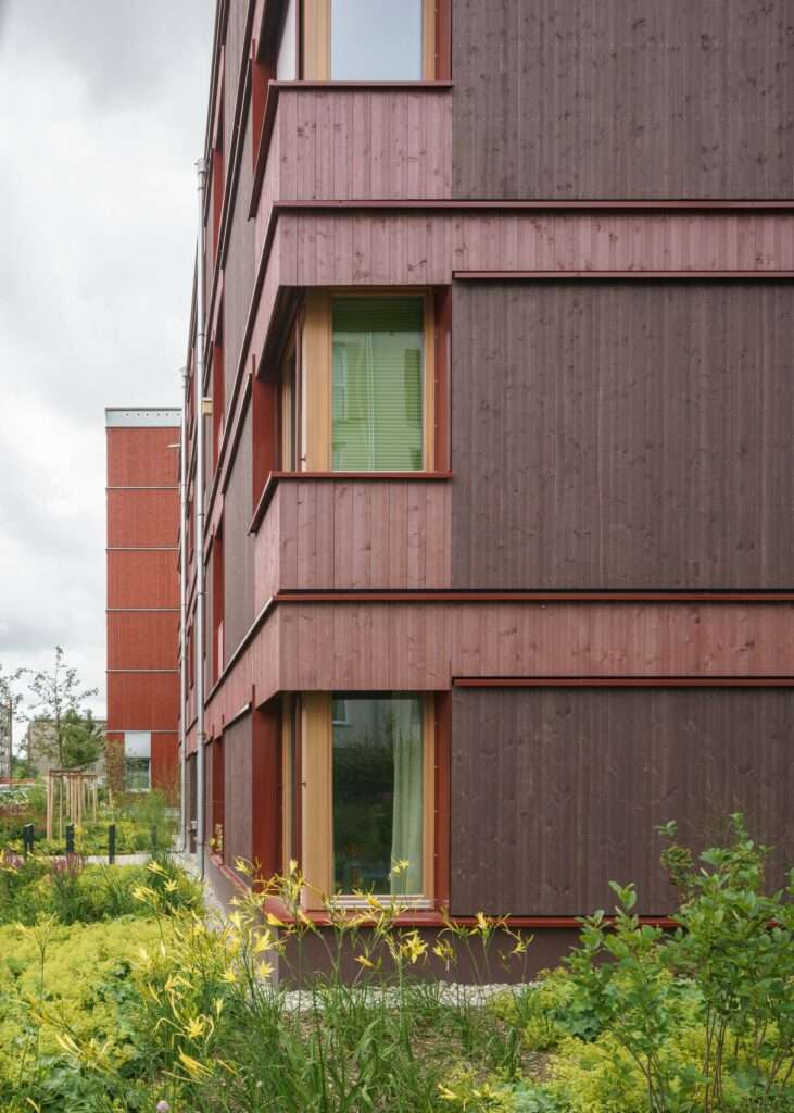 Detail of local larch wood cladding and staggered corner windows on a modern residential building in Munich.