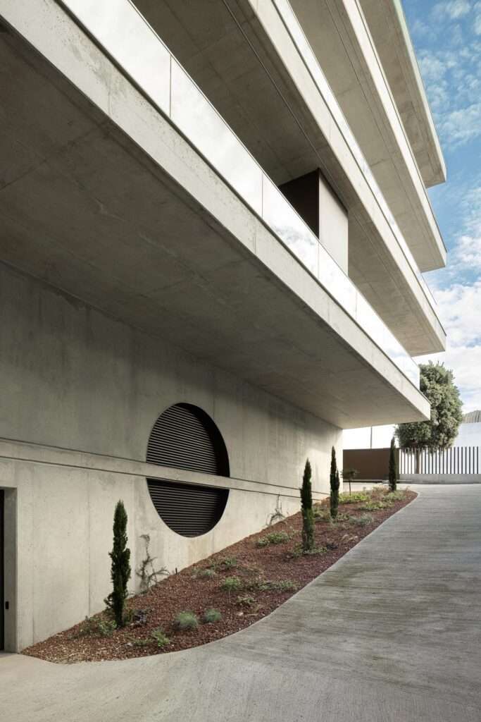 Exposed concrete wall with a large circular ventilation opening next to the underground parking ramp at Scala-Mare.