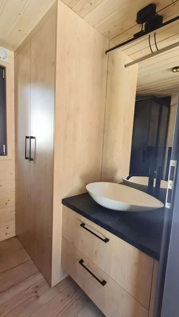 Modern bathroom interior in the Samuel house featuring a white vessel sink and minimalist wood vanity.