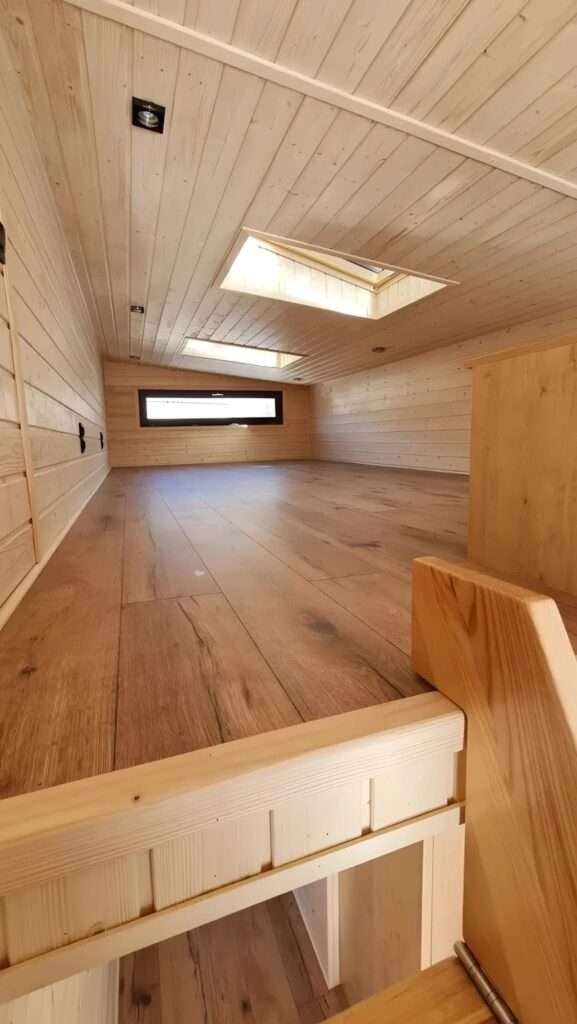 View of the 13-square-meter mezzanine floor with wooden surfaces and a skylight.